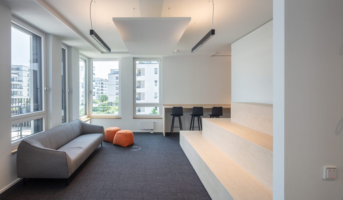 Moderner Aufenthaltsbereich mit Sofa, Sitzstufen und heller Bürogestaltung in den Reiterstaffel Offices Köln